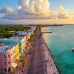"Aerial view of Duval Street in Key West with pastel buildings, turquoise waters, and a sunset sailboat in September's low season, featuring Southernmost Point buoy and looming storm clouds in the distance."