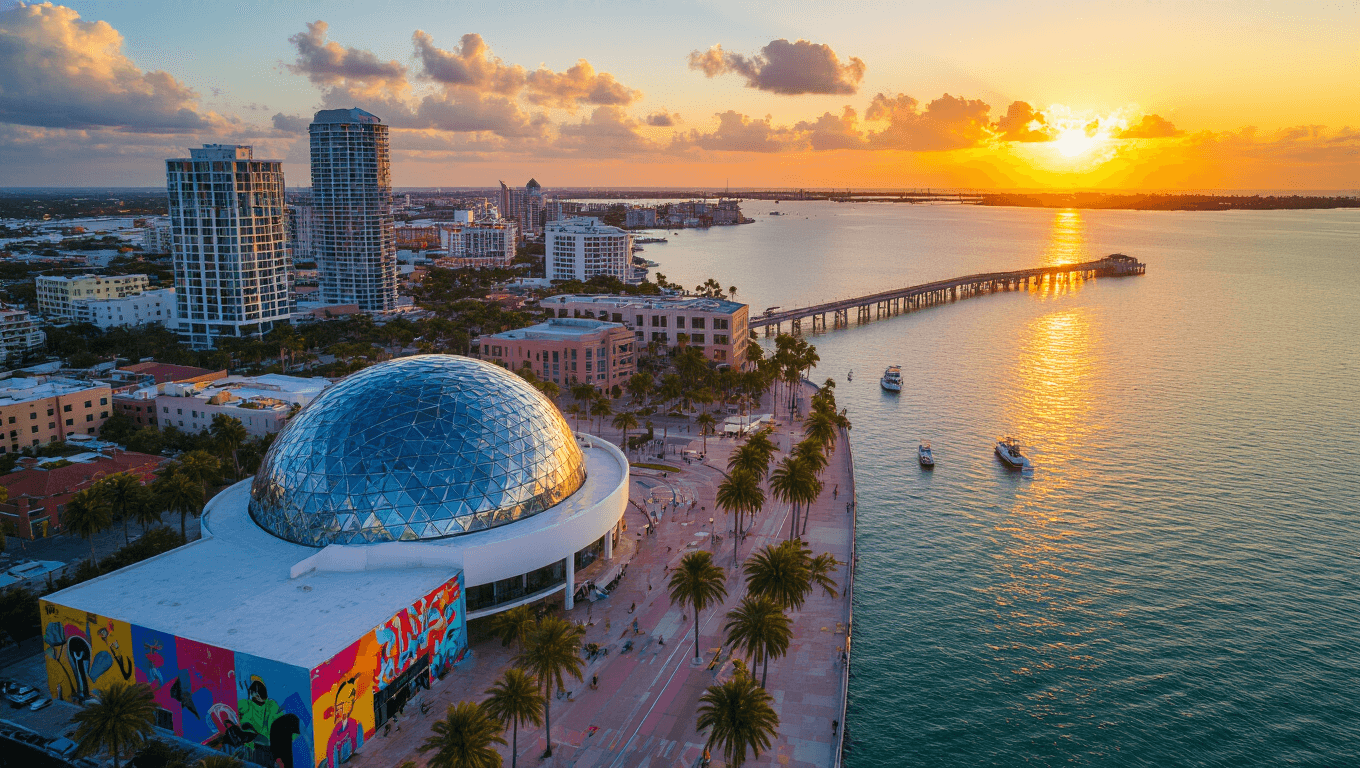 "Aerial view of St. Petersburg, Florida at sunset featuring the St. Pete Pier, Dali Museum and street murals with surrounding palm trees and boats in Tampa Bay"