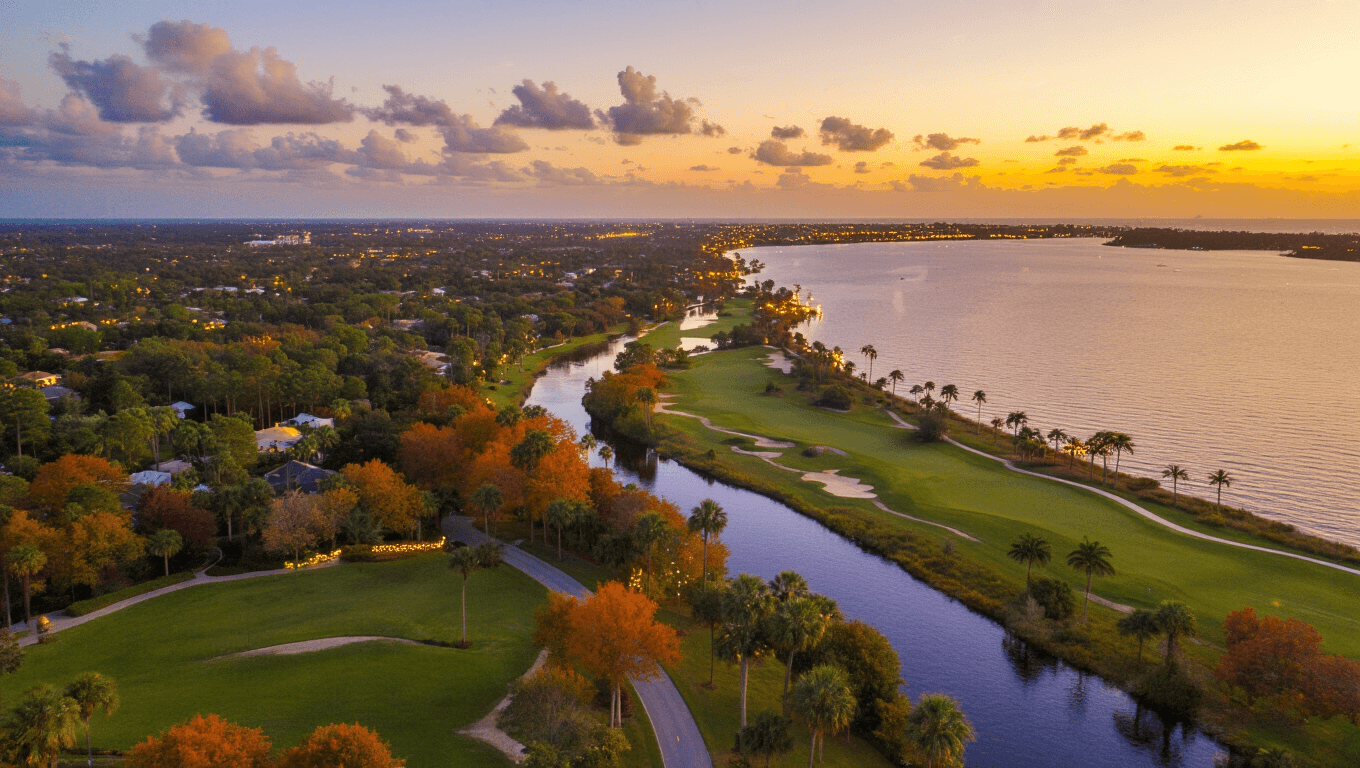 "Panoramic aerial view of Port St. Lucie during golden hour, highlighting St. Lucie River, Botanical Gardens, a golf course, maritime hammock forests, and holiday lights decoration."